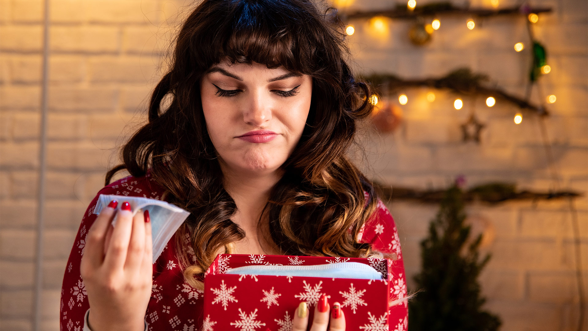 Woman looks disappointed after opening wrapped present. 