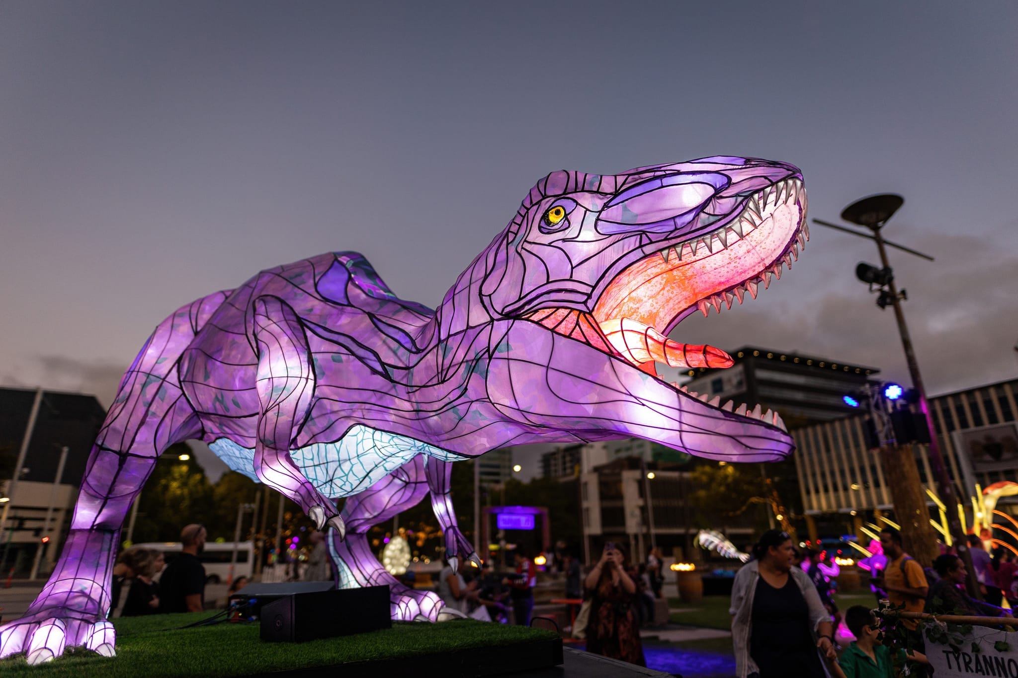 Illuminated T-Rex attracting community members at &ldquo;Before Us&rdquo;