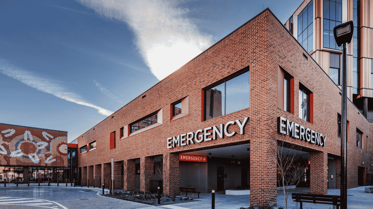 A hospital building with 'emergency' signage displayed at the front.