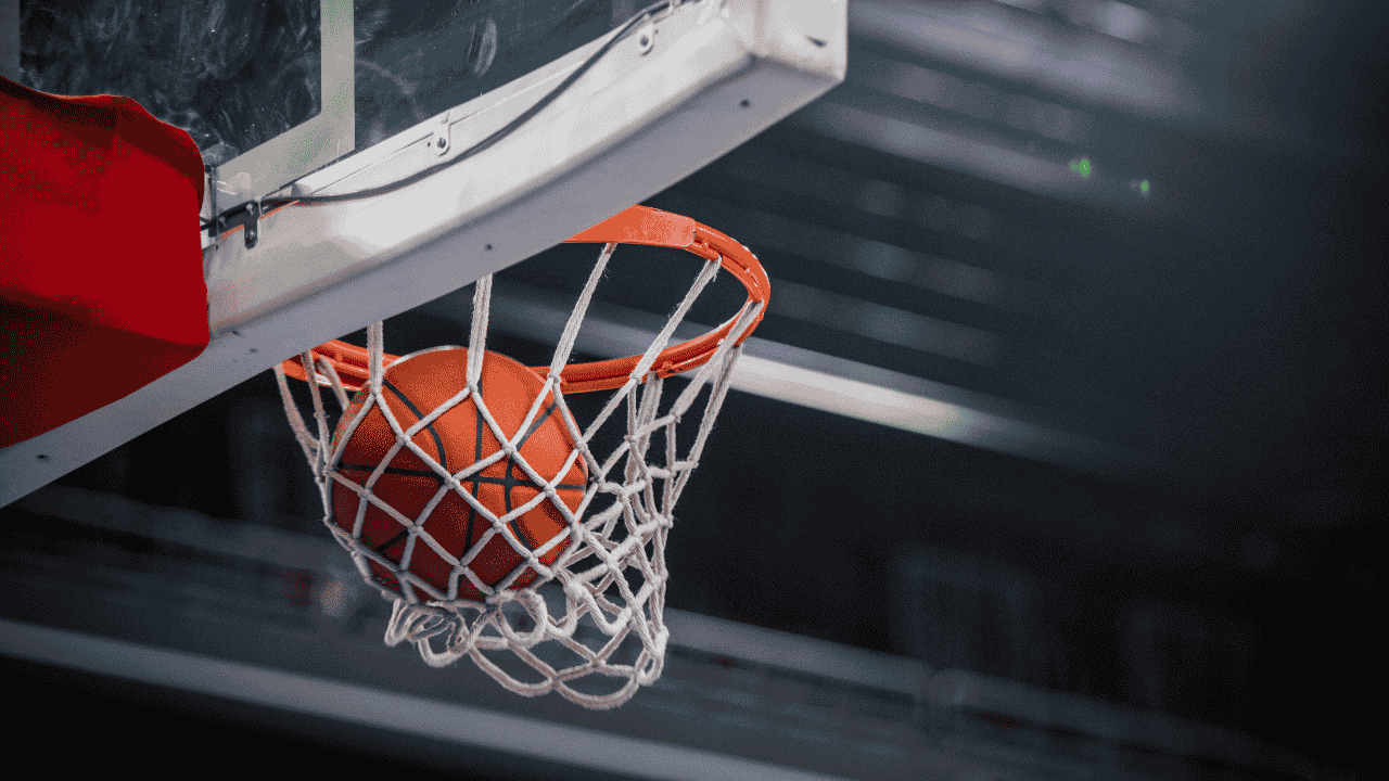 A netted basketball hoop with a basketball going through it.