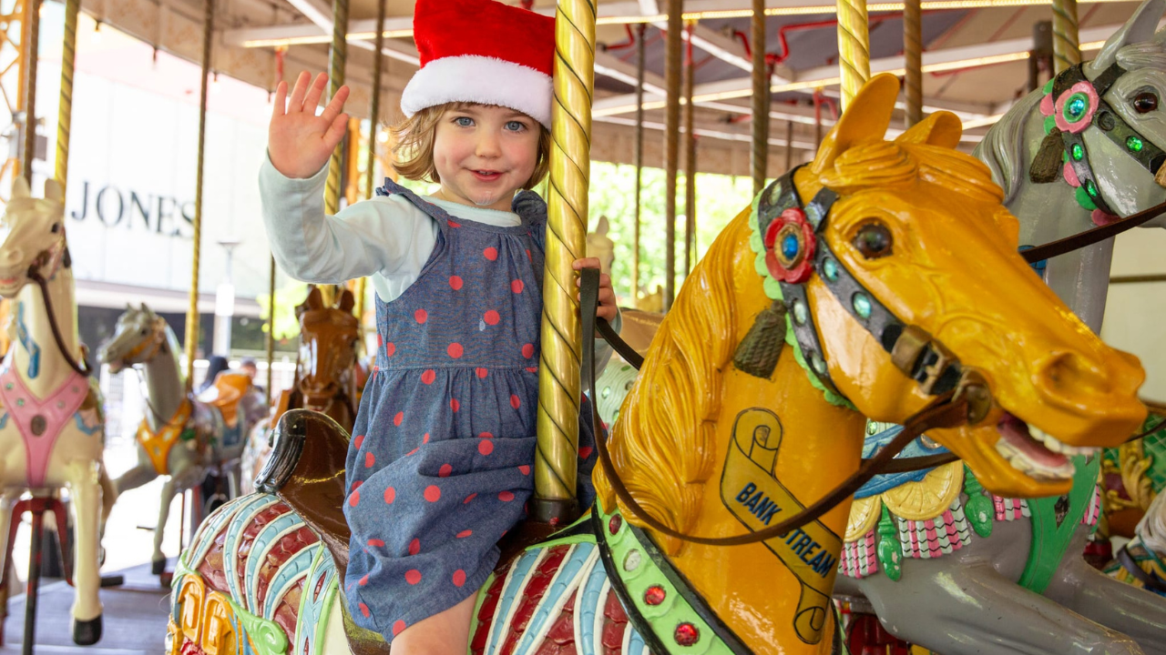 A local girl enjoys a free merry-go-round in the City Centre.