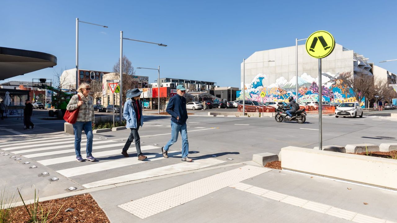 Three people using pedestrian crossing at the Elouera and Mort Streets intersection.