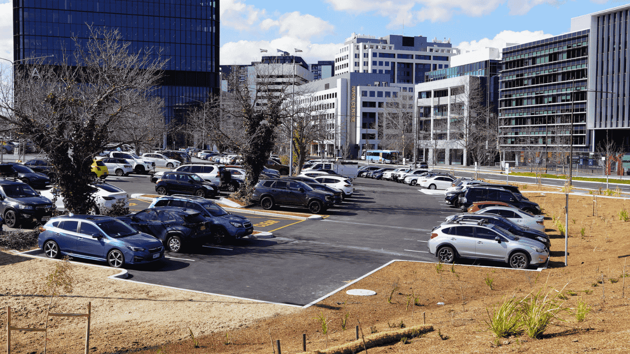 Open air car park with cars parked and buildings in the background.