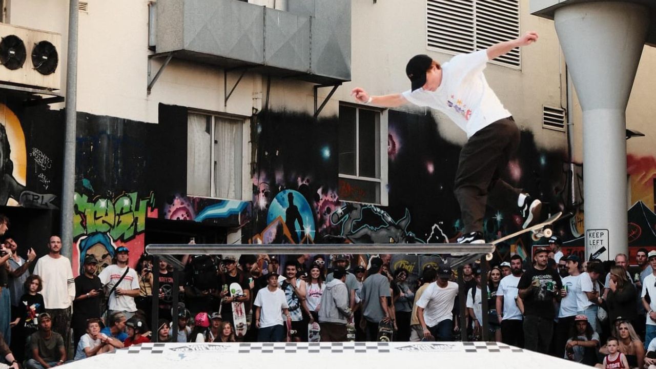 Skateboarder does trick on rail. 