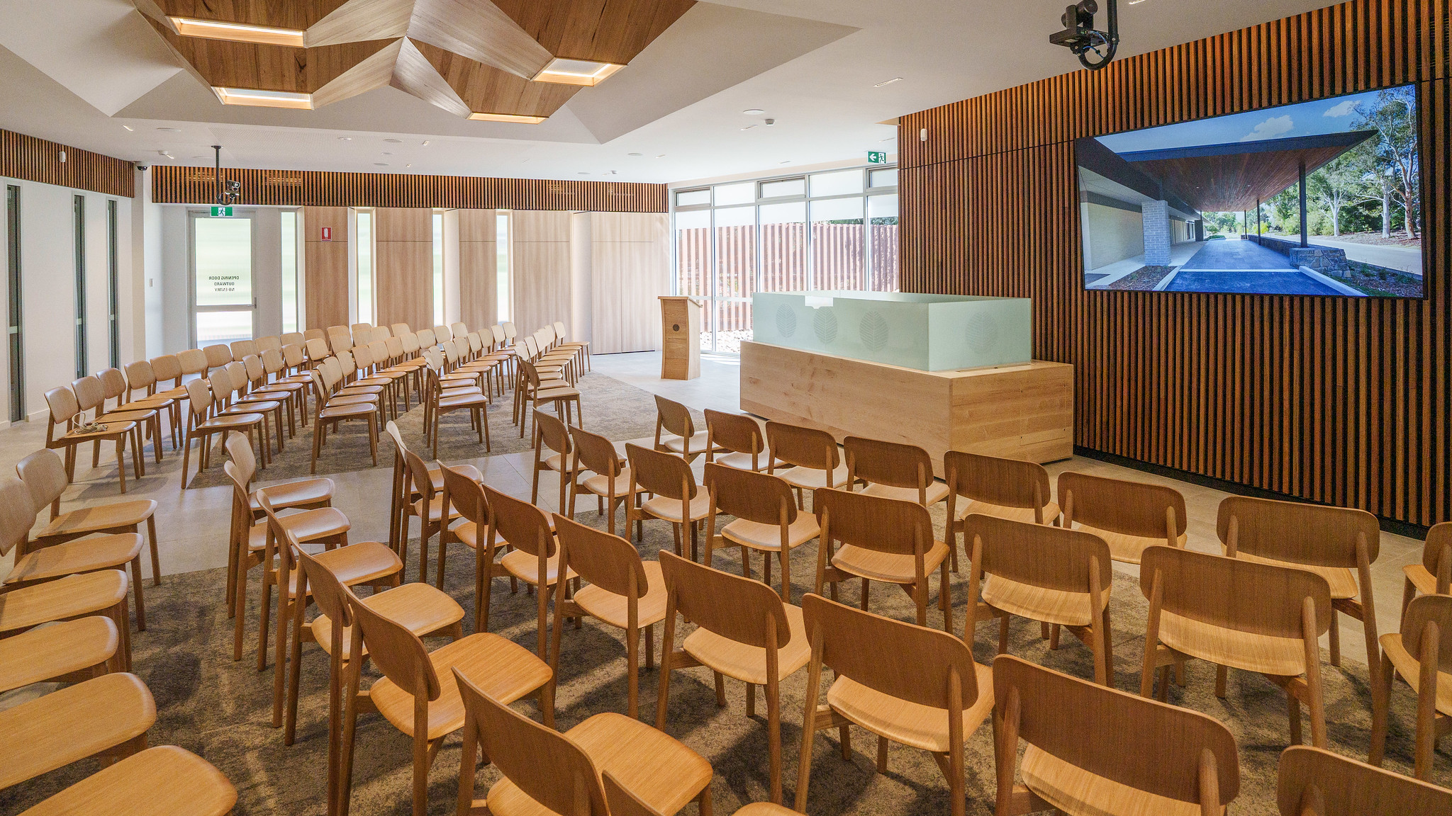 A room with curved rows of chairs, a big screen and a raised stand.