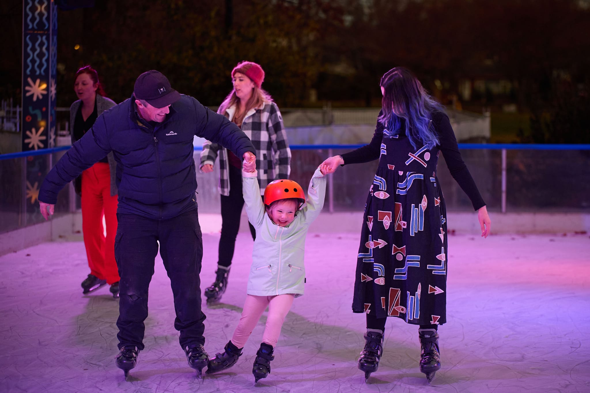 Two adults and a child ice skating in Glebe Park