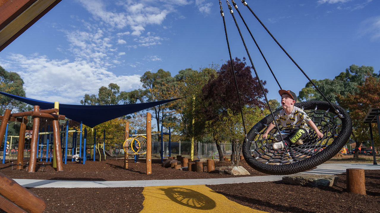 A child plays on a swing in a playground.