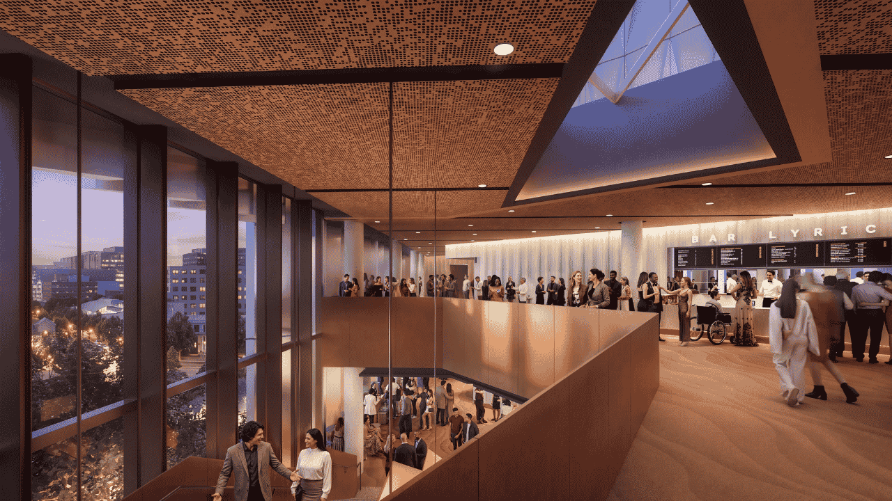 Architectural rendering of a theatre foyer and bar area with warm timber finishes, floor-to-ceiling windows, and a large central staircase connecting multiple levels.