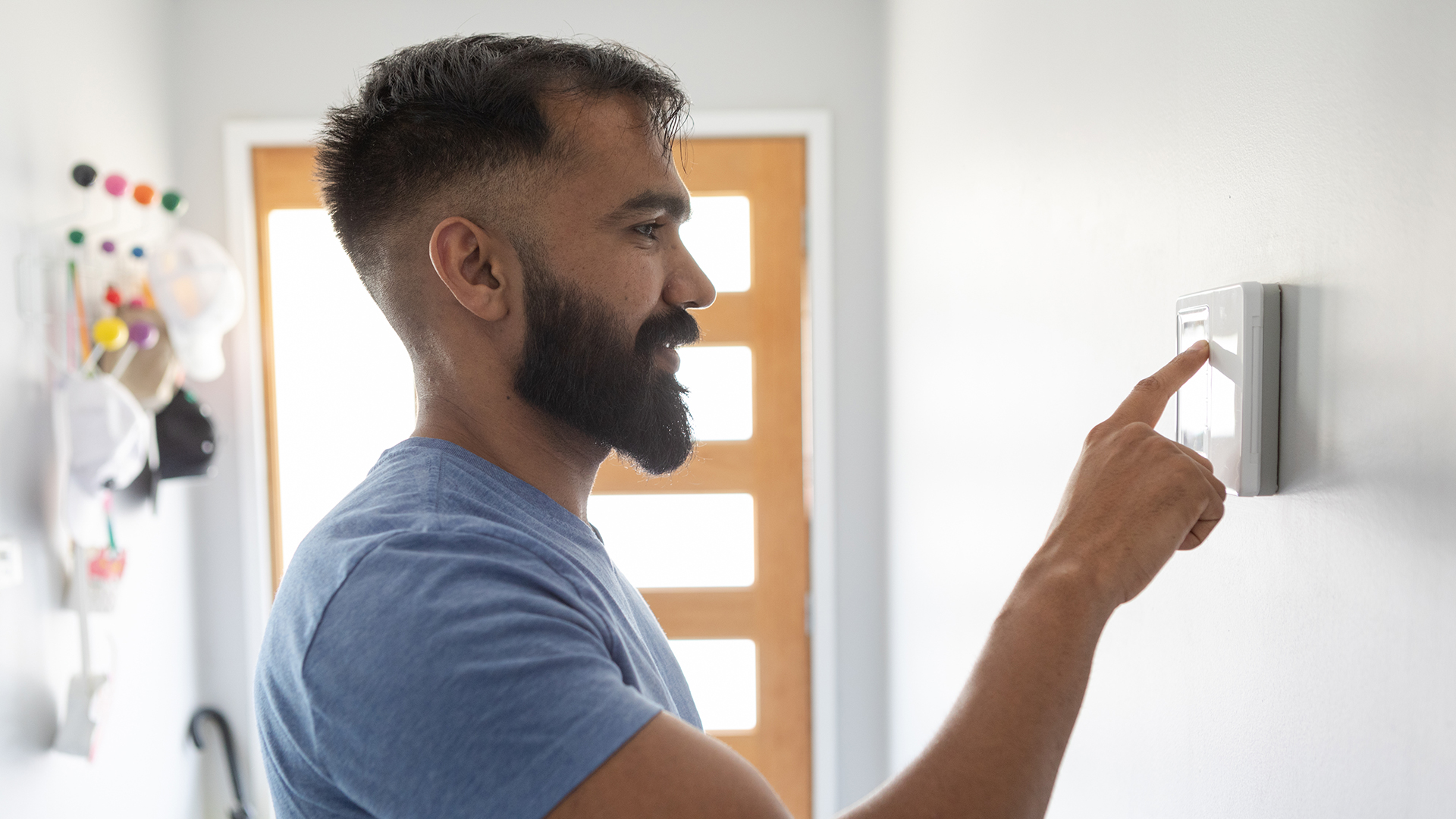 A man adjusts an air-conditioning thermostat