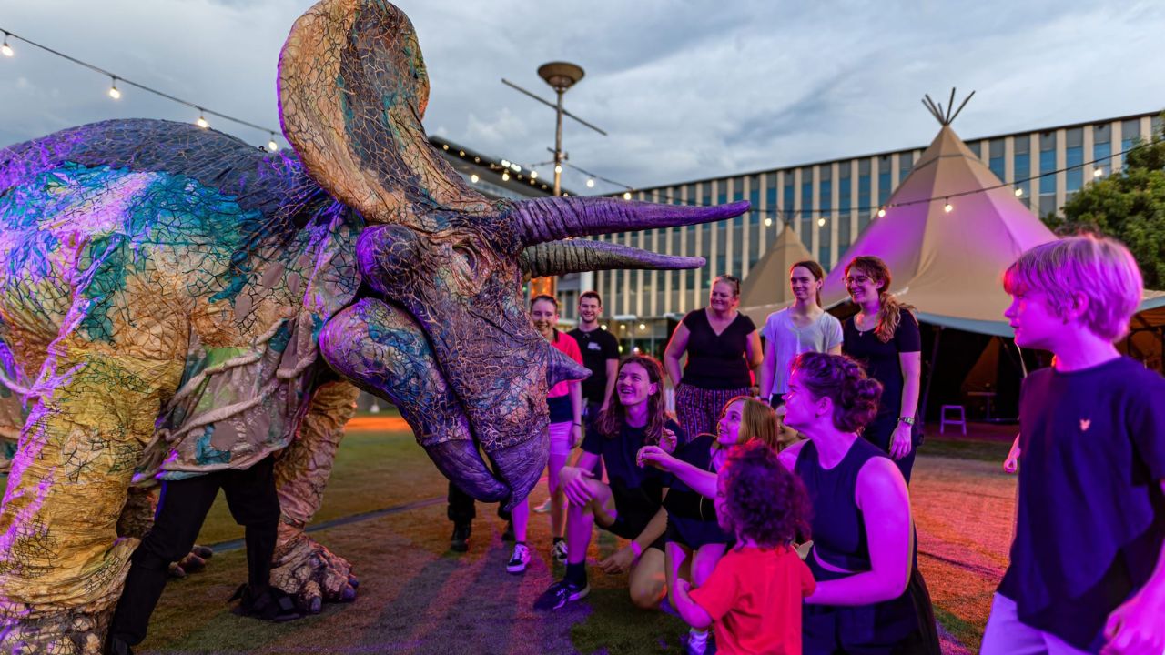 Dinosaur puppet interacts with children in Civic Square. 