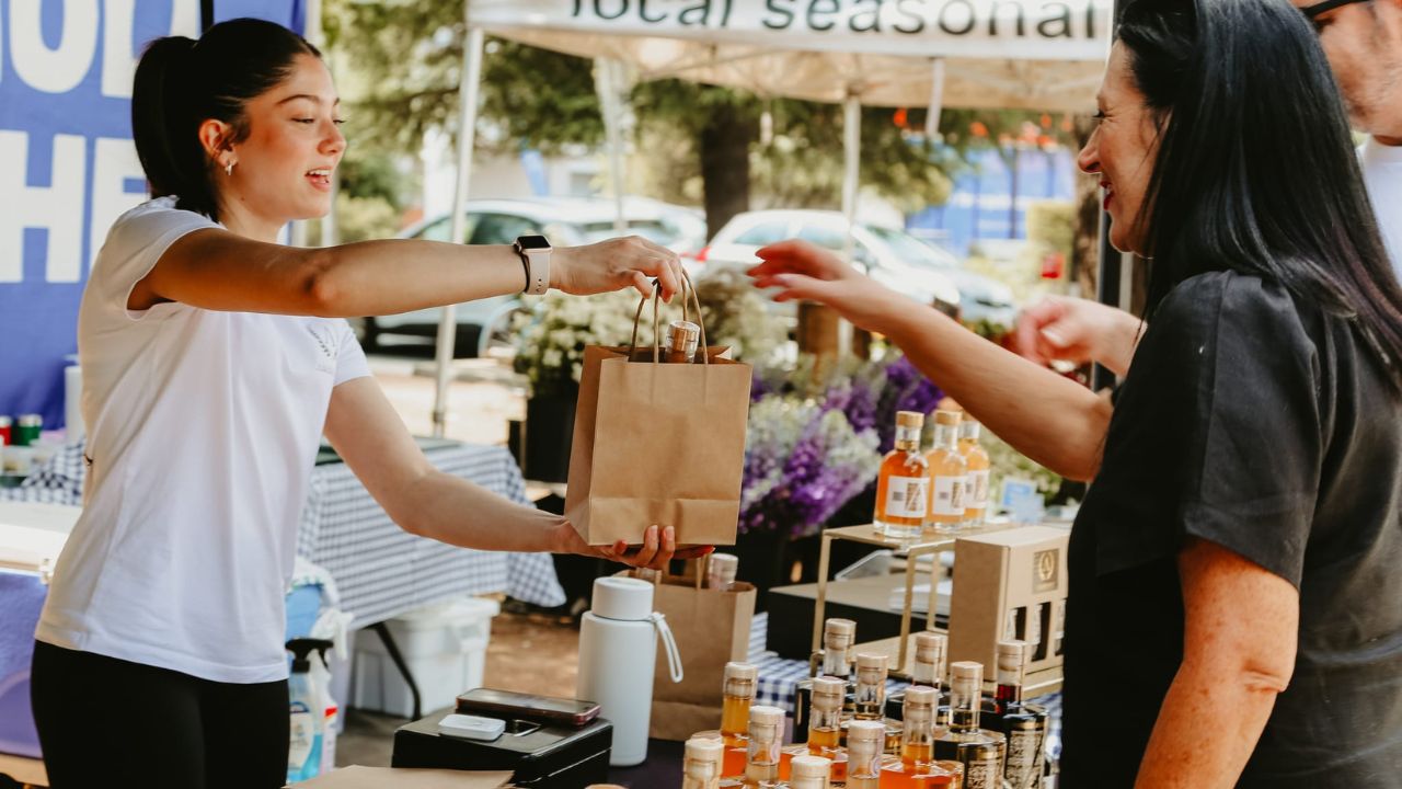 Woman serves customer at market stall. 