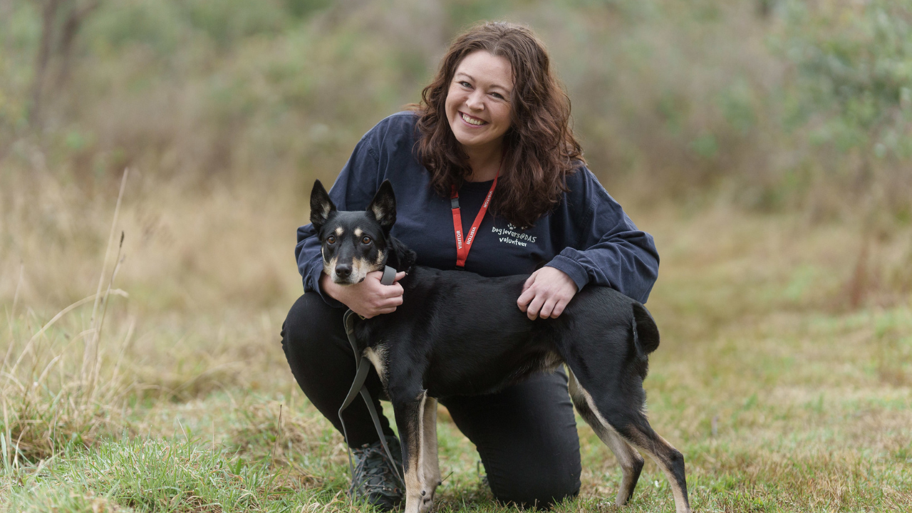 A woman smiles with a dog.