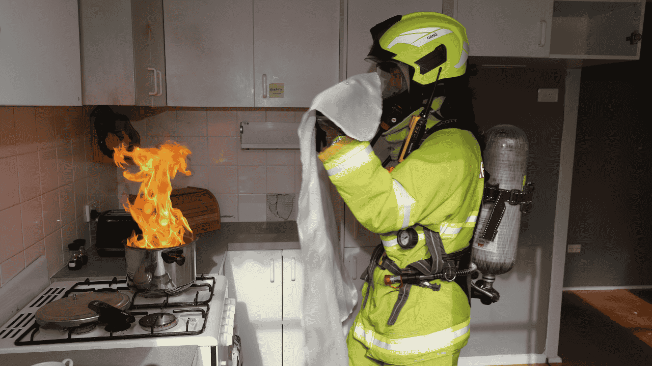 A fireman covers a fire on a stove top.