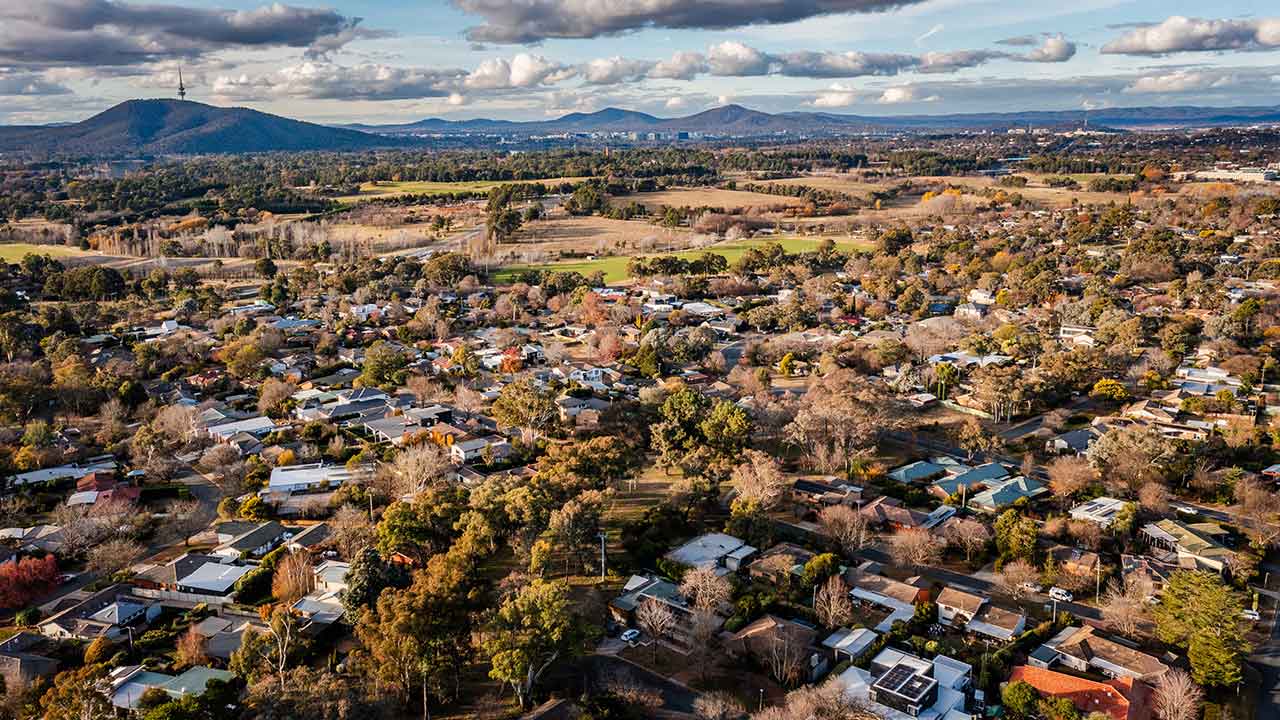 A drone shot showing Canberra housing from above. Telstra Tower is in the background.