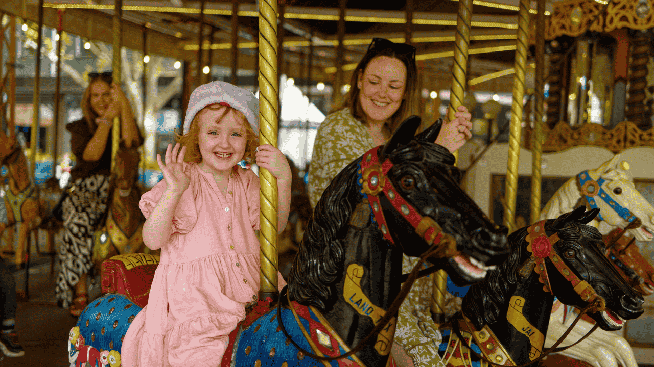 A child and adult ride on a merry-go-round.