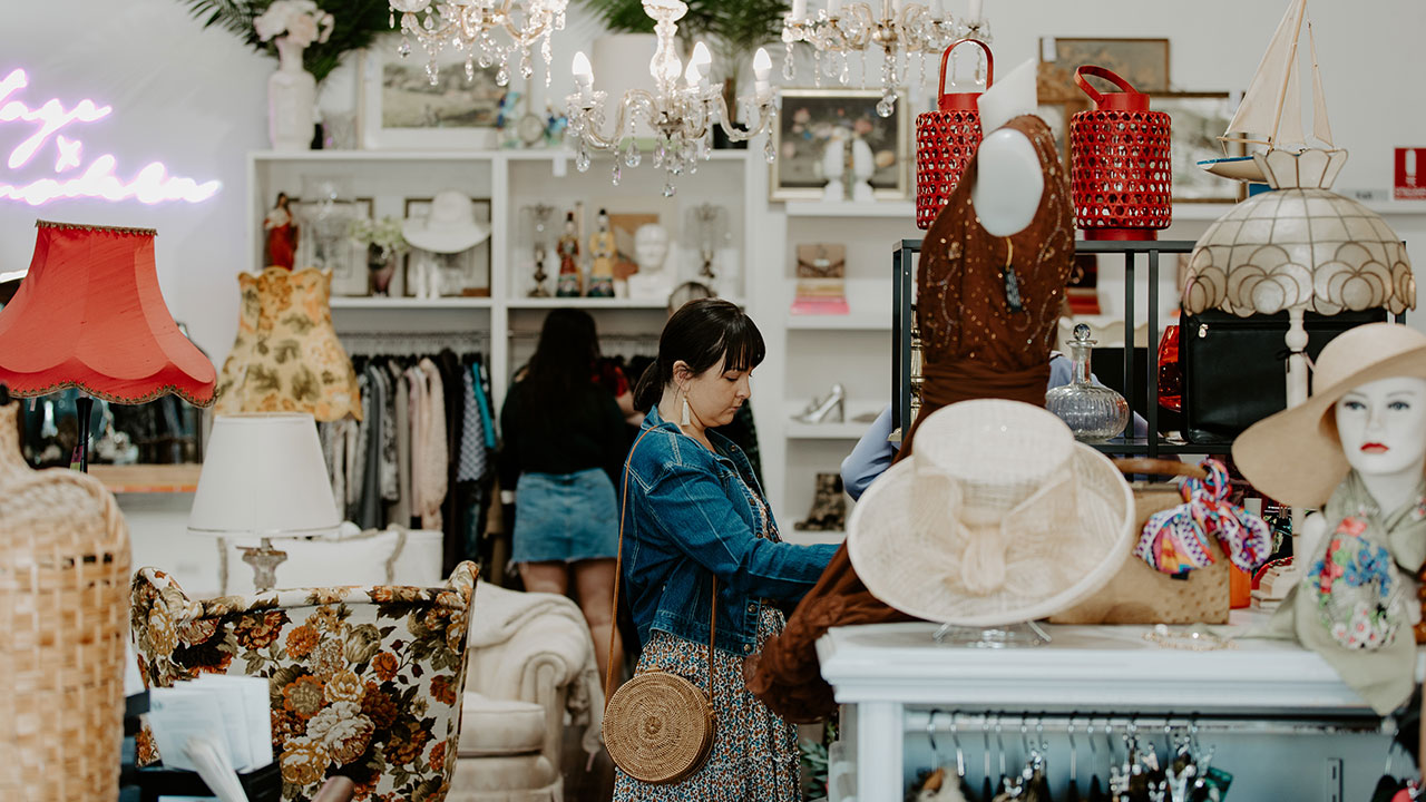 A woman looks through racks of clothing in a store.