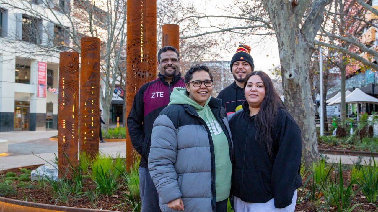 Four people stand with artwork