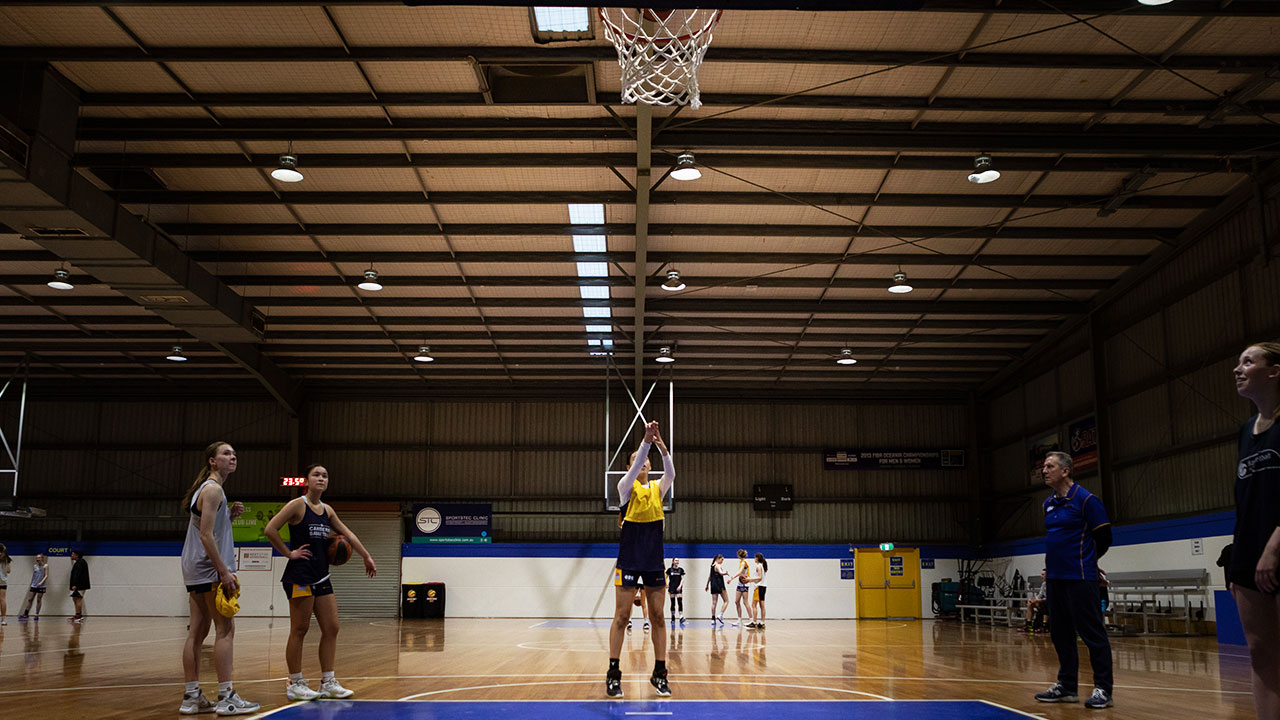 A person in a yellow jersey throws a ball.