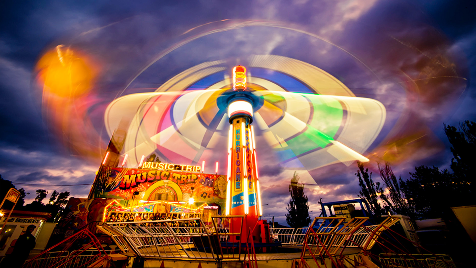 Night image of a bright ride in Sideshow alley called 'Music Trip' 
