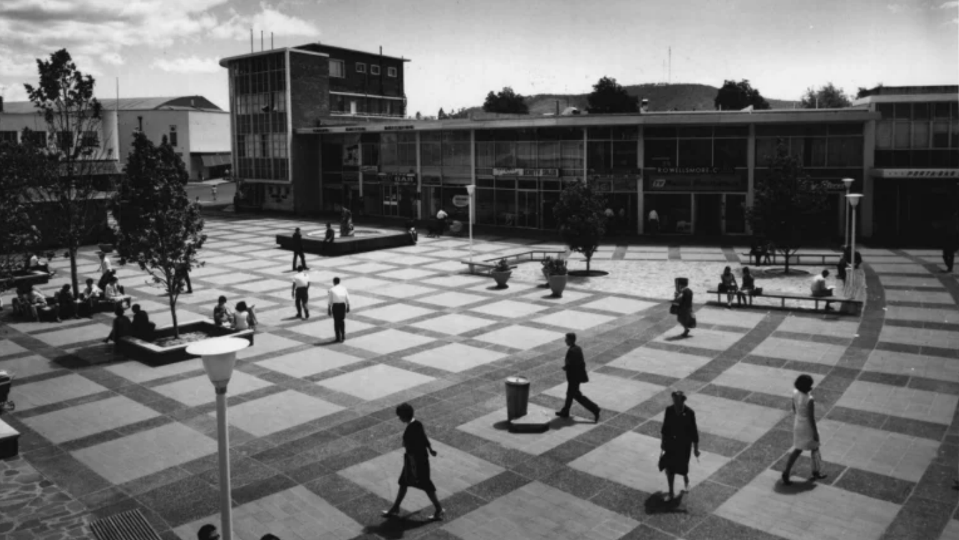 An old photo of Garema Place as a square with chequered paving and lots of people walking around