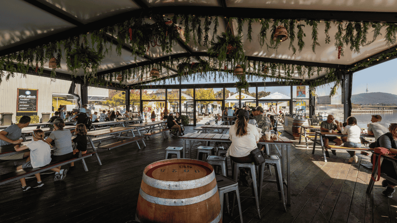 A restaurant inside a marquee with people seated on chairs and tables with Christmas decorations hanging above.
