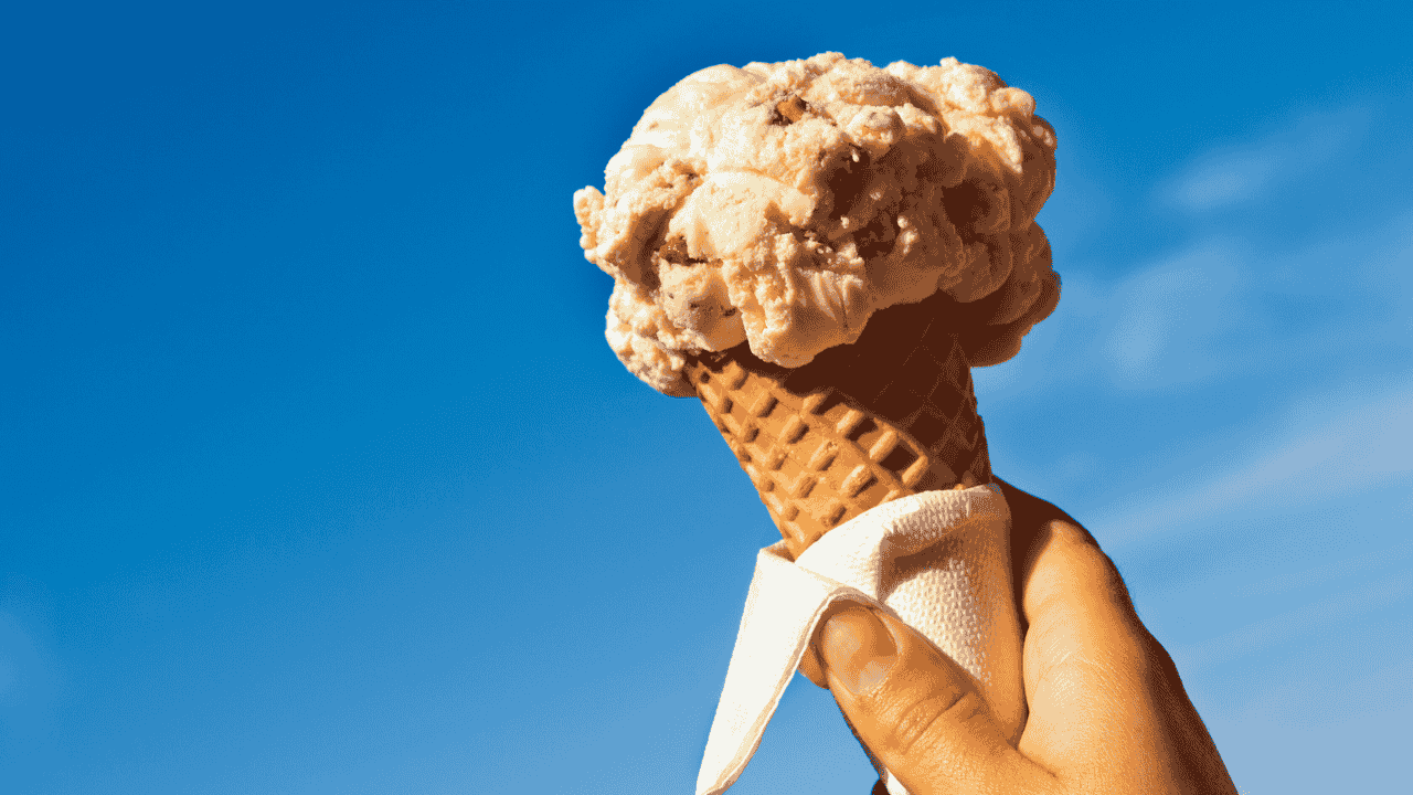 A person holds an ice-cream in a waffle cone.