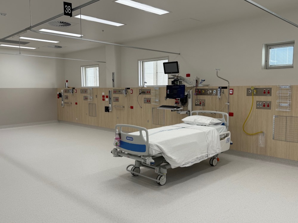 A hospital bed in an otherwise empty bay, surrounded by medical equipment