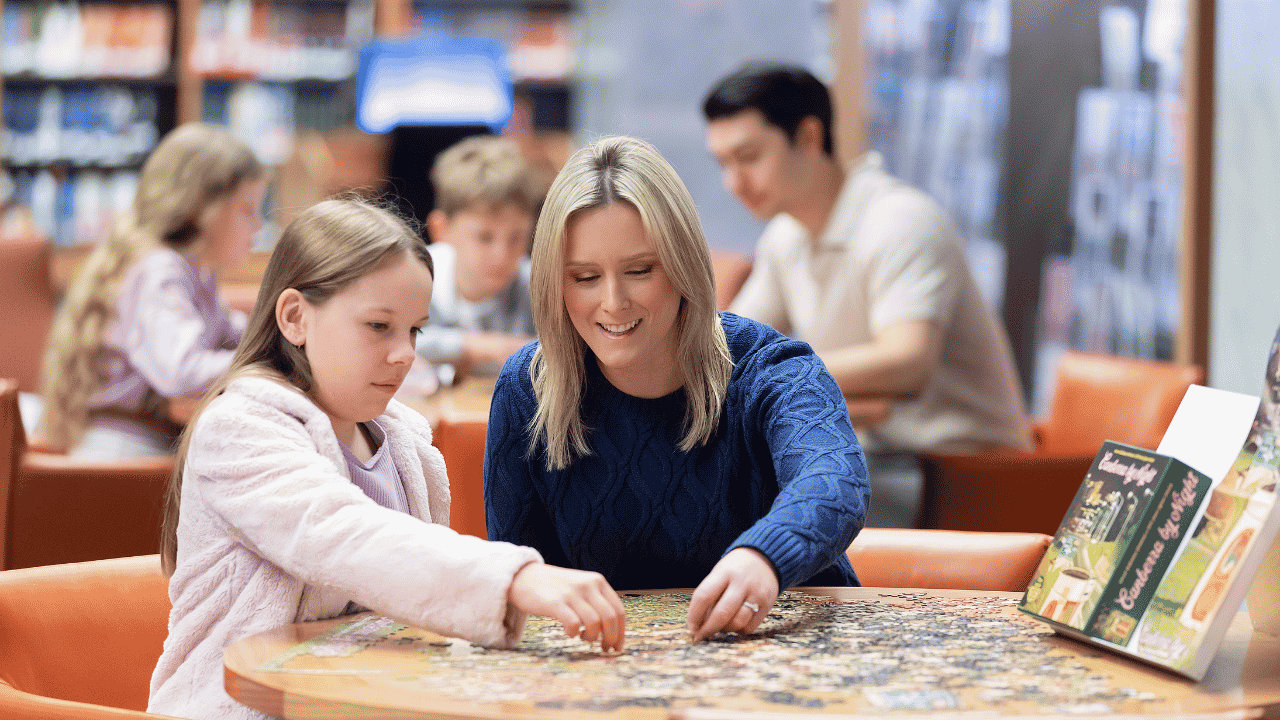 A child and women are sat together doing a jigsaw puzzle.