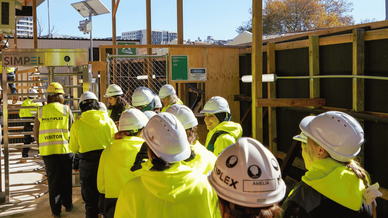 A group of people wearing hard hats and high vis walk onto a construction site.