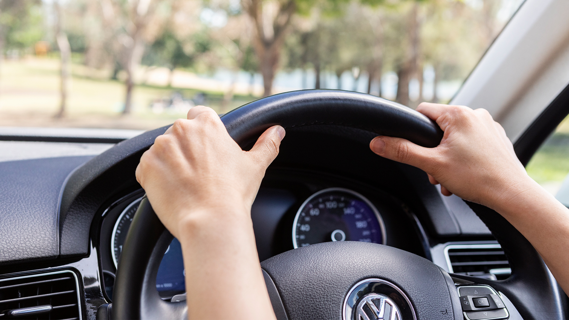 Close up of hands holding steering wheel inside car