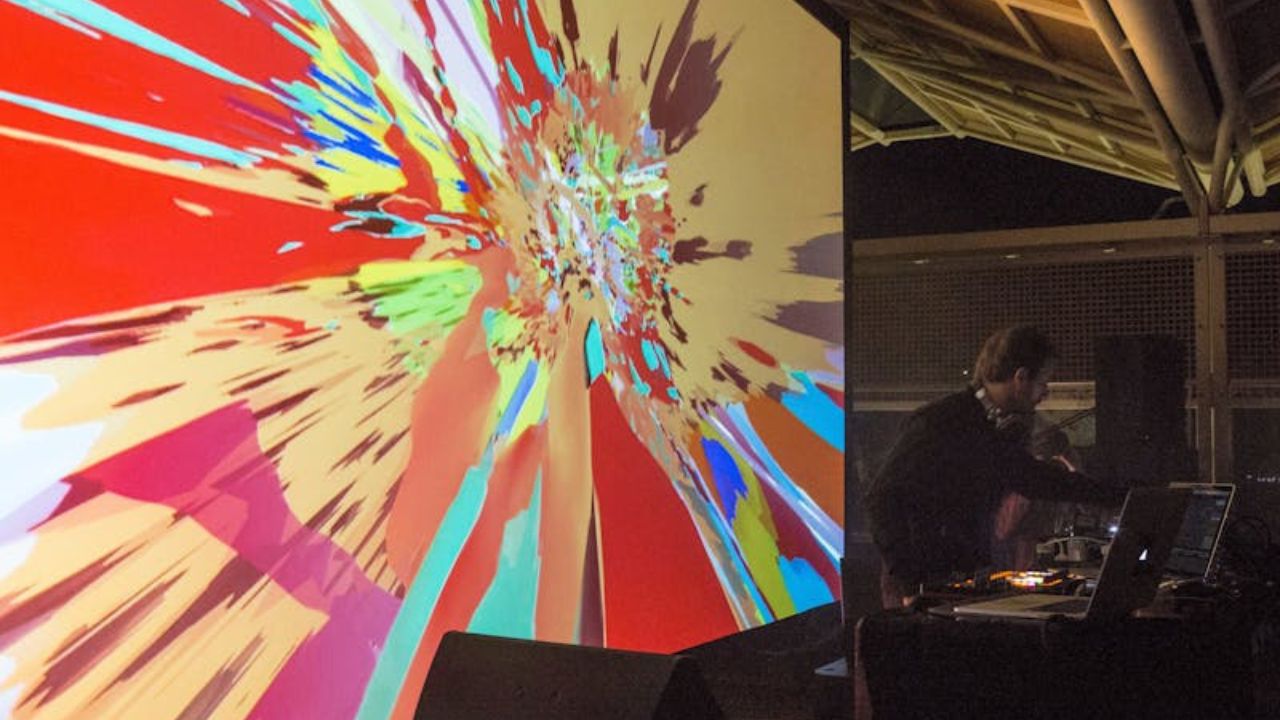 Dj performing in front of projection.
