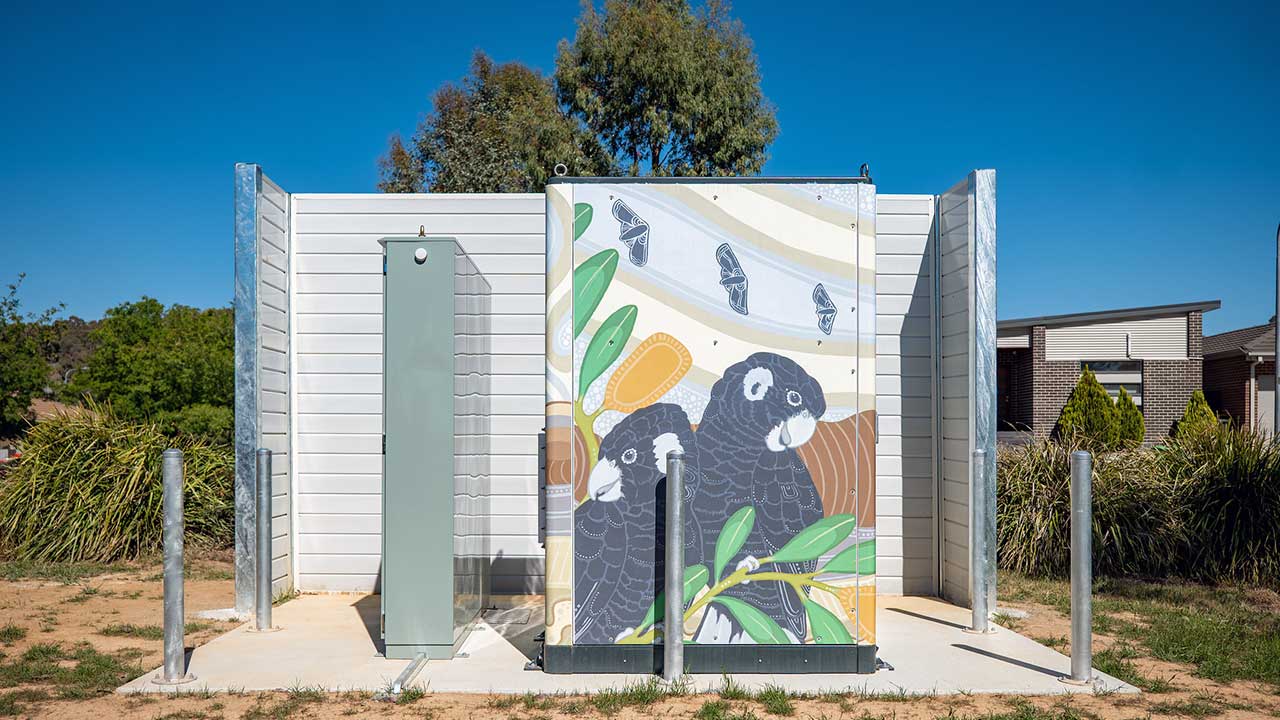 A large outdoor electrical box decorated with a mural of black cockatoos.