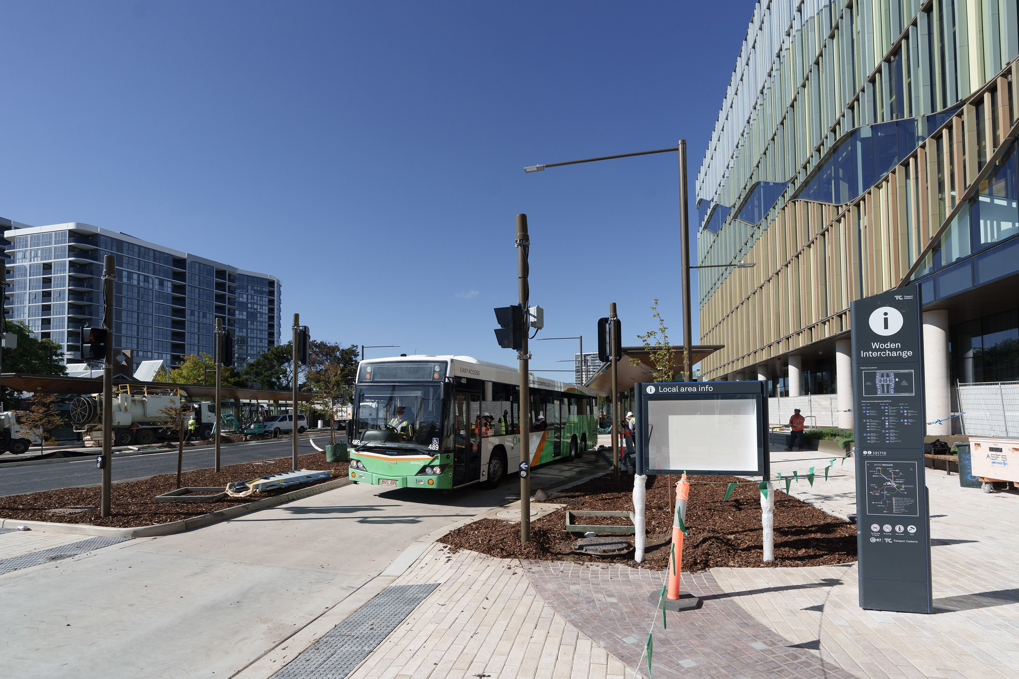 A green bus stops in a bus interchange.