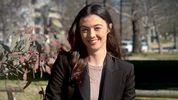 Georgia Brennan is sitting outside, smiling and looking at the camera.
