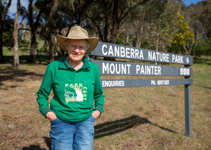 A woman stands in front of a sign at a nature reserve. 