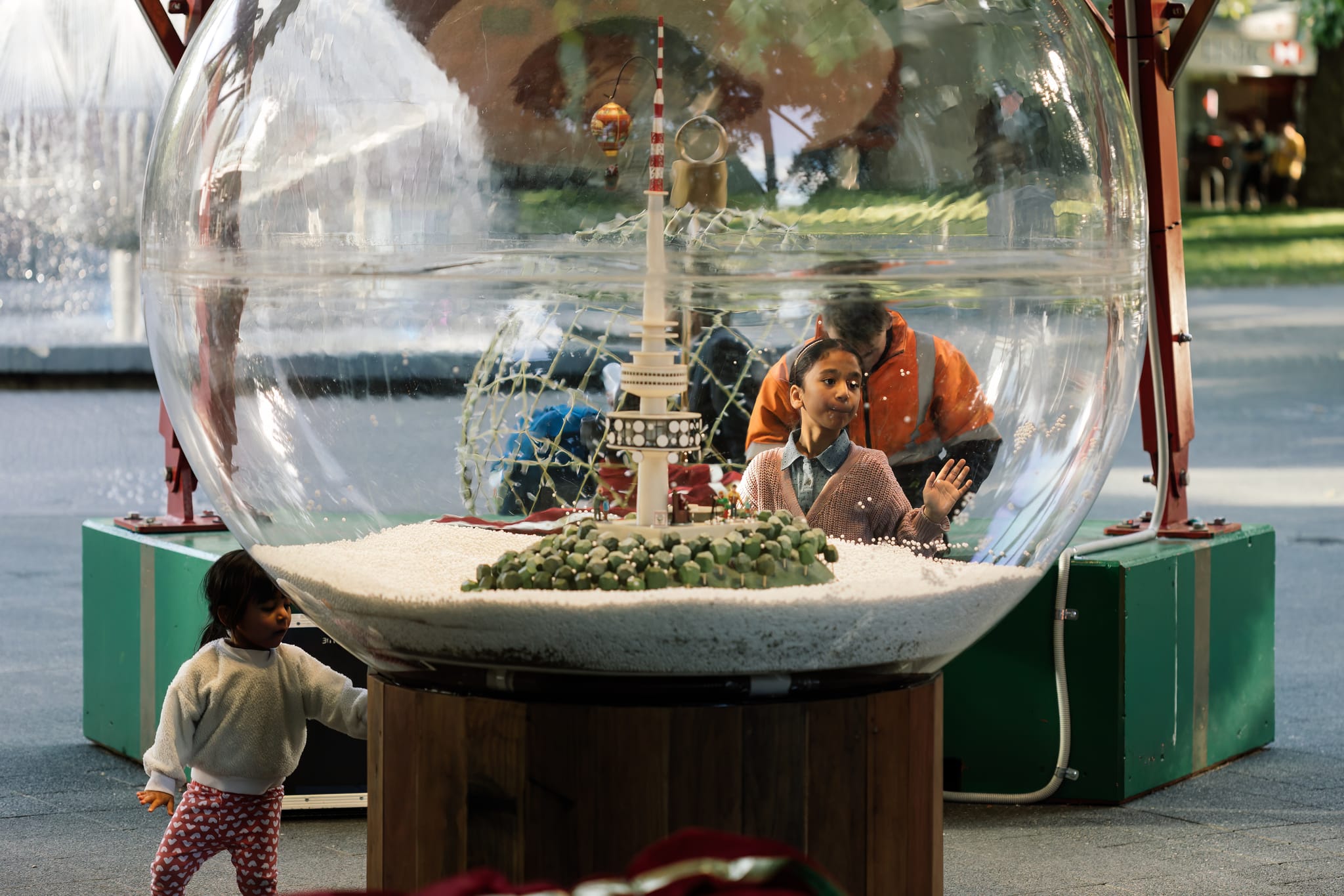 Two young girls look into a snowglobe depicting a wintry Black Mountain tower scene. 