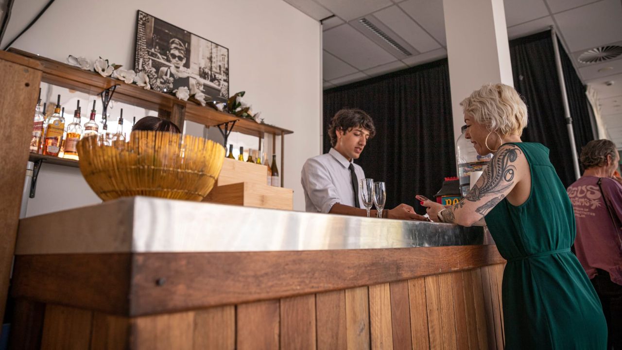 Server at snack bar serving drinks.