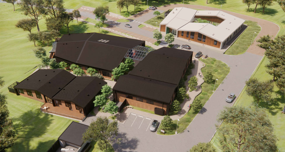 A render depicting an aerial view of a health centre with multiple buildings surrounded by landscaped gardens and parking areas. Solar panels are visible on some of the rooftops.