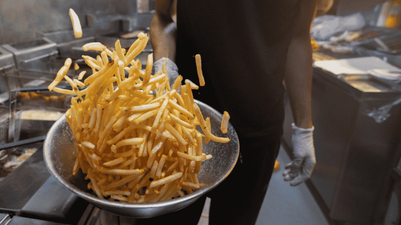 Image of chef tossing chips in a bowl.