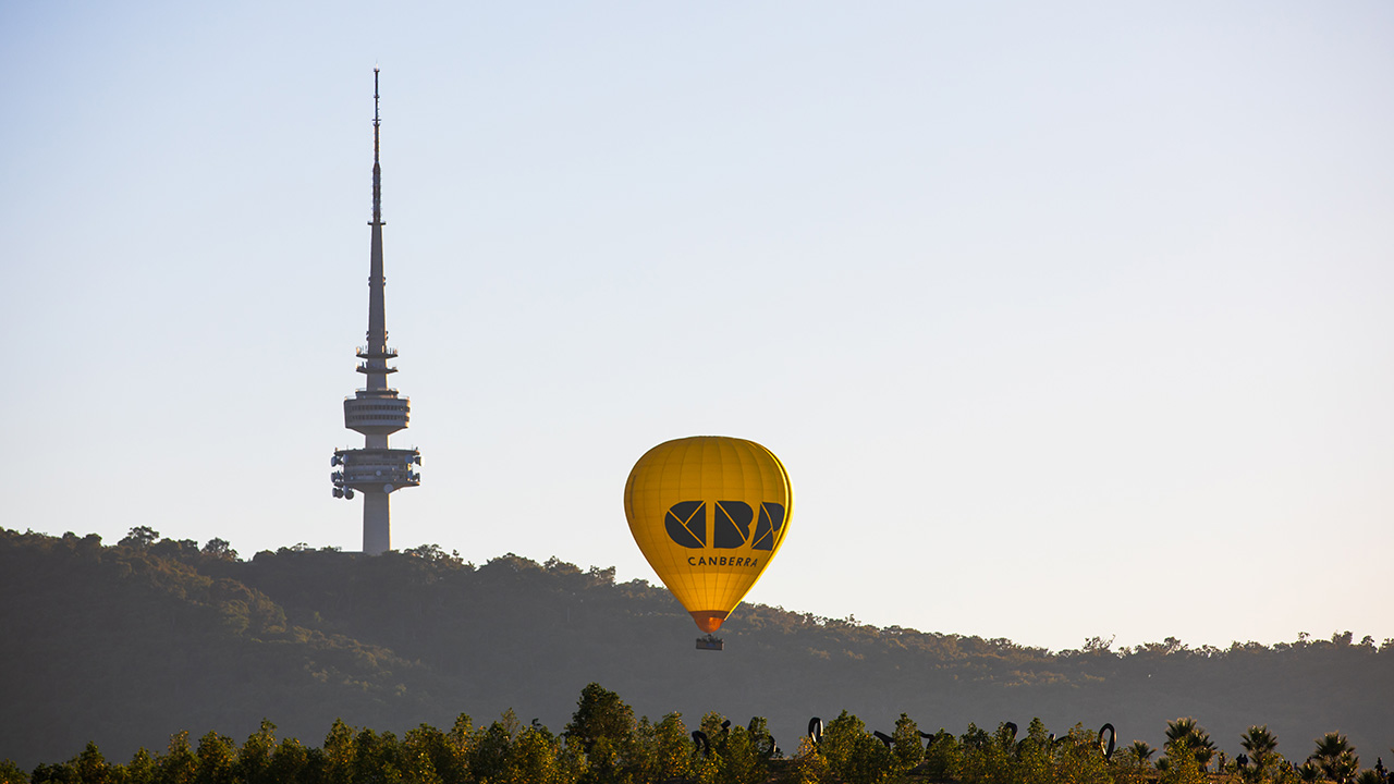 A large tower on a mountain with a hot air balloon in front of it.