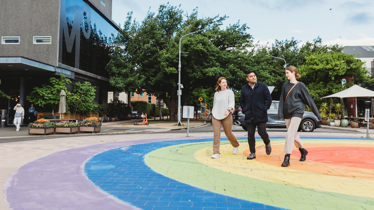 three young people walking across the rainbow round about in Braddon ACT