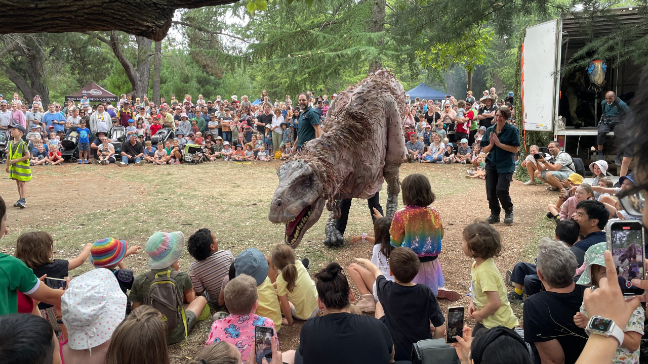 A crowd of thousands watch a life-sized dinosaur puppet at the Jurassic Haig Park event earlier in 2023.