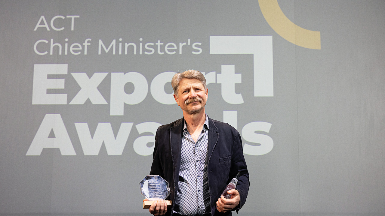 A man with a moustache holding a trophy.