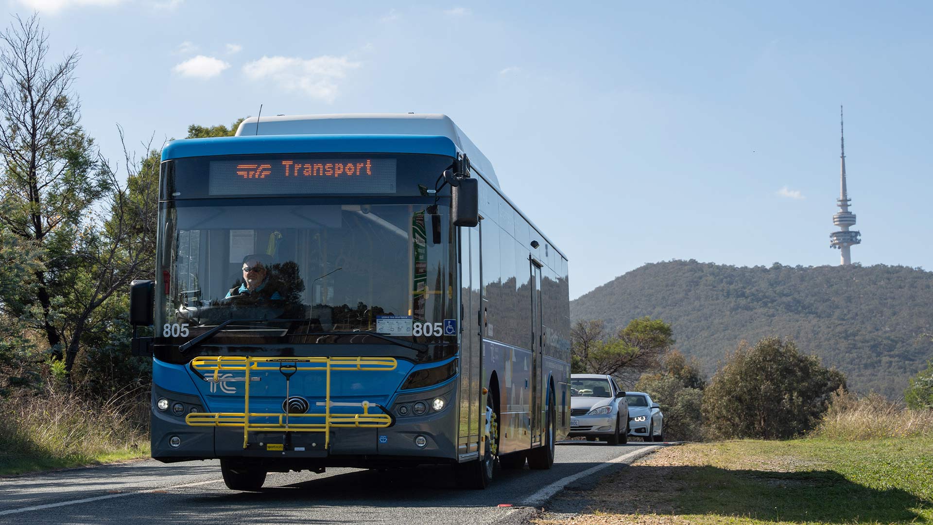 Blue electric bus driving on road.