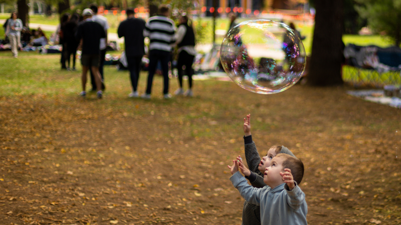 A couple of children try and pop a giant bubble at a Play Outside Day in Haig Park