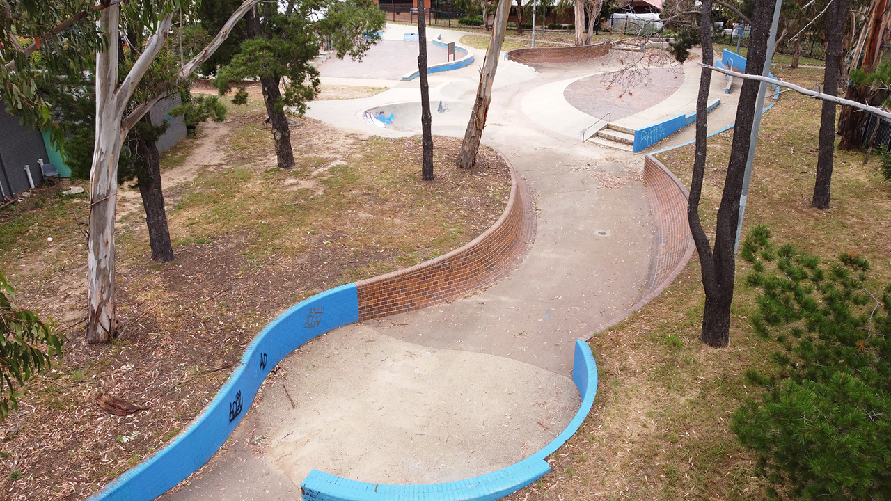 An overhead photo of a skate park with curved walls, some painted blue.
