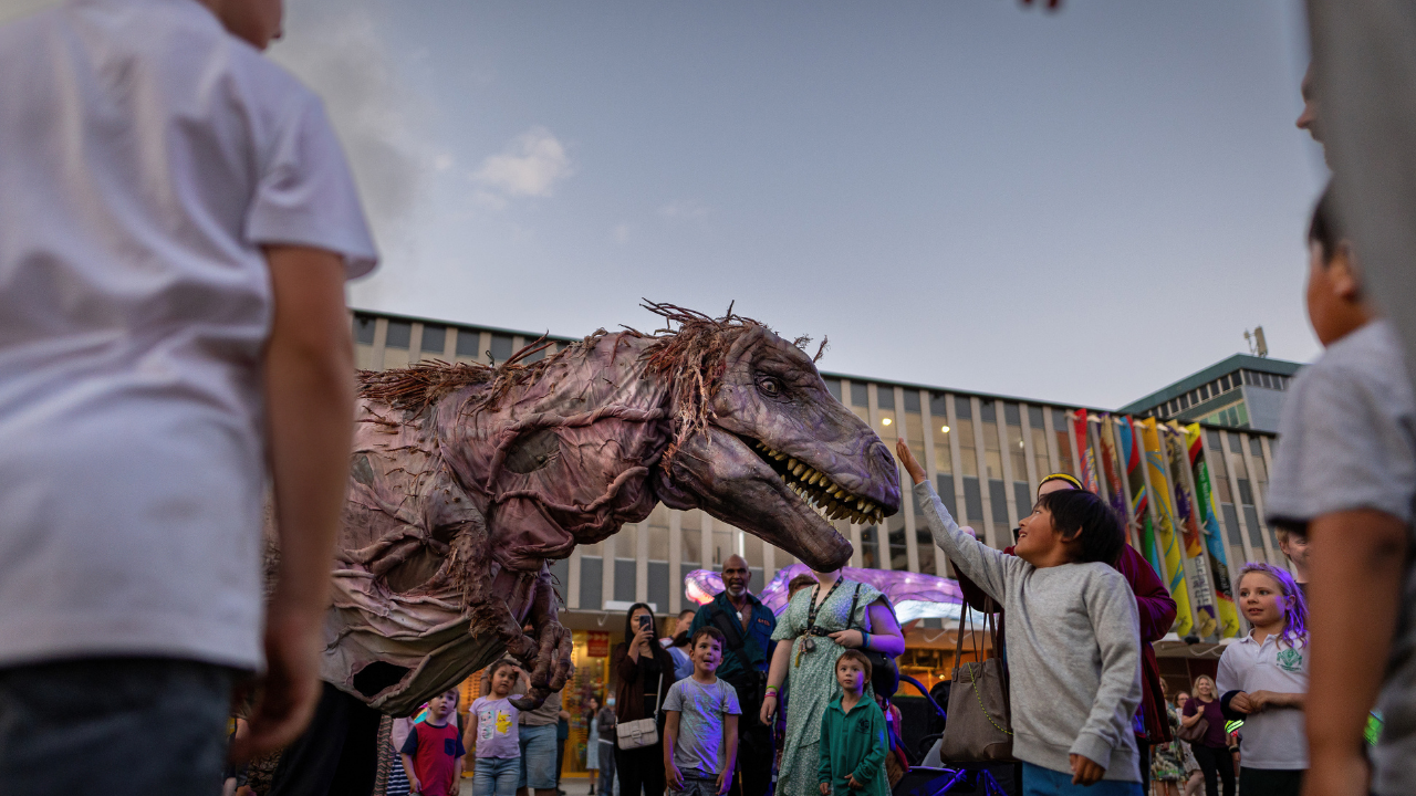 A giant dinosaur puppet delights the crowd at City Illuminations at Enlighten Festival